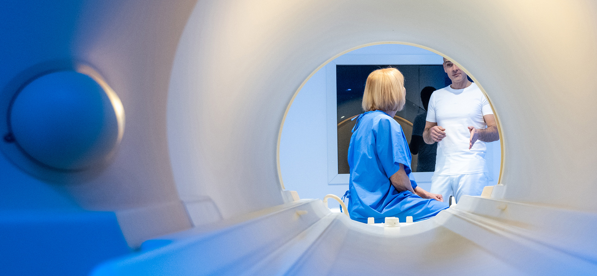 A look inside an MRI scanner with a patient and a doctor talking outside of the MRI scanner